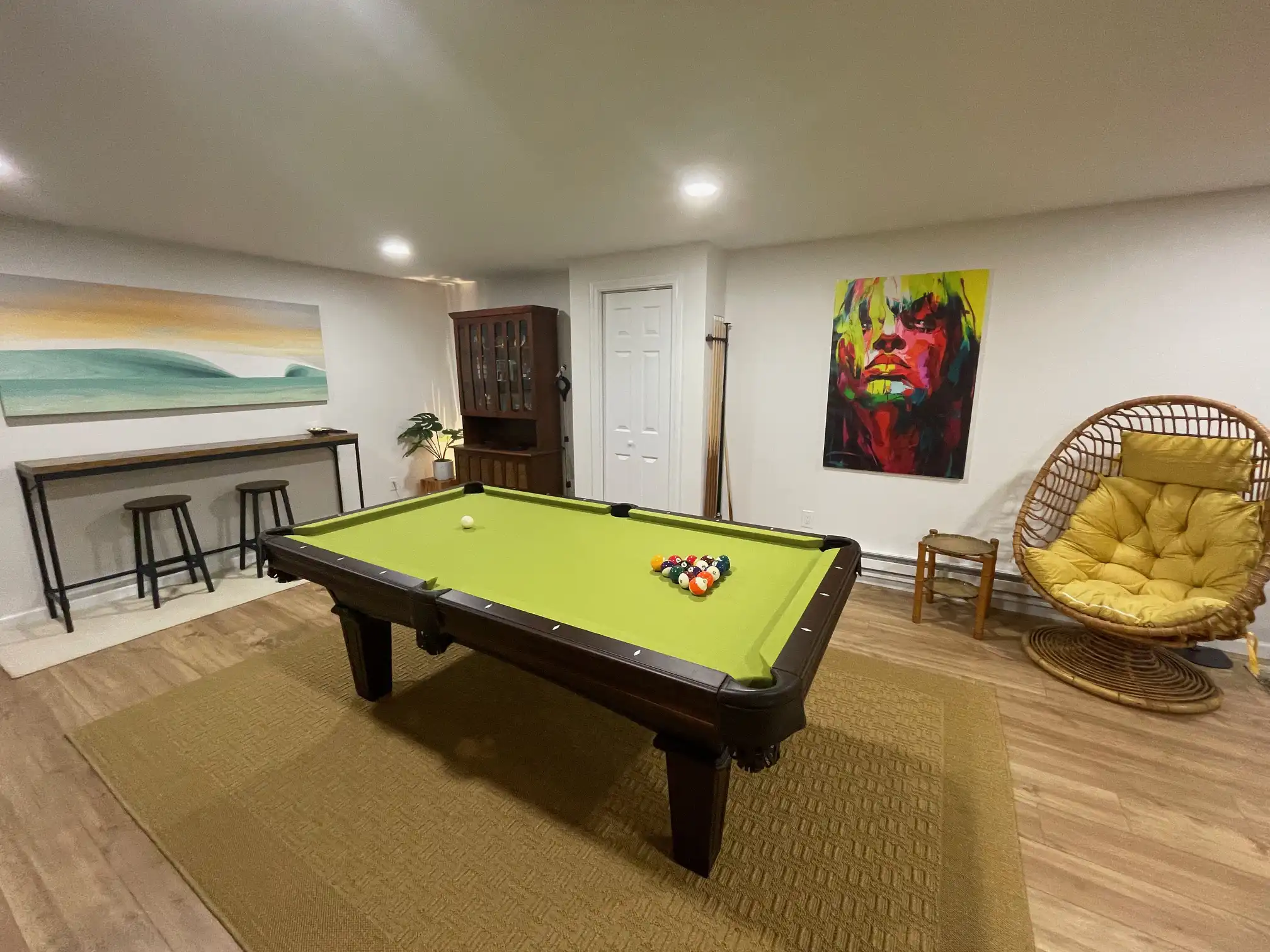 chartreuse, green, yellow Olhausen pool table with a modern painting of a woman's face on the wall