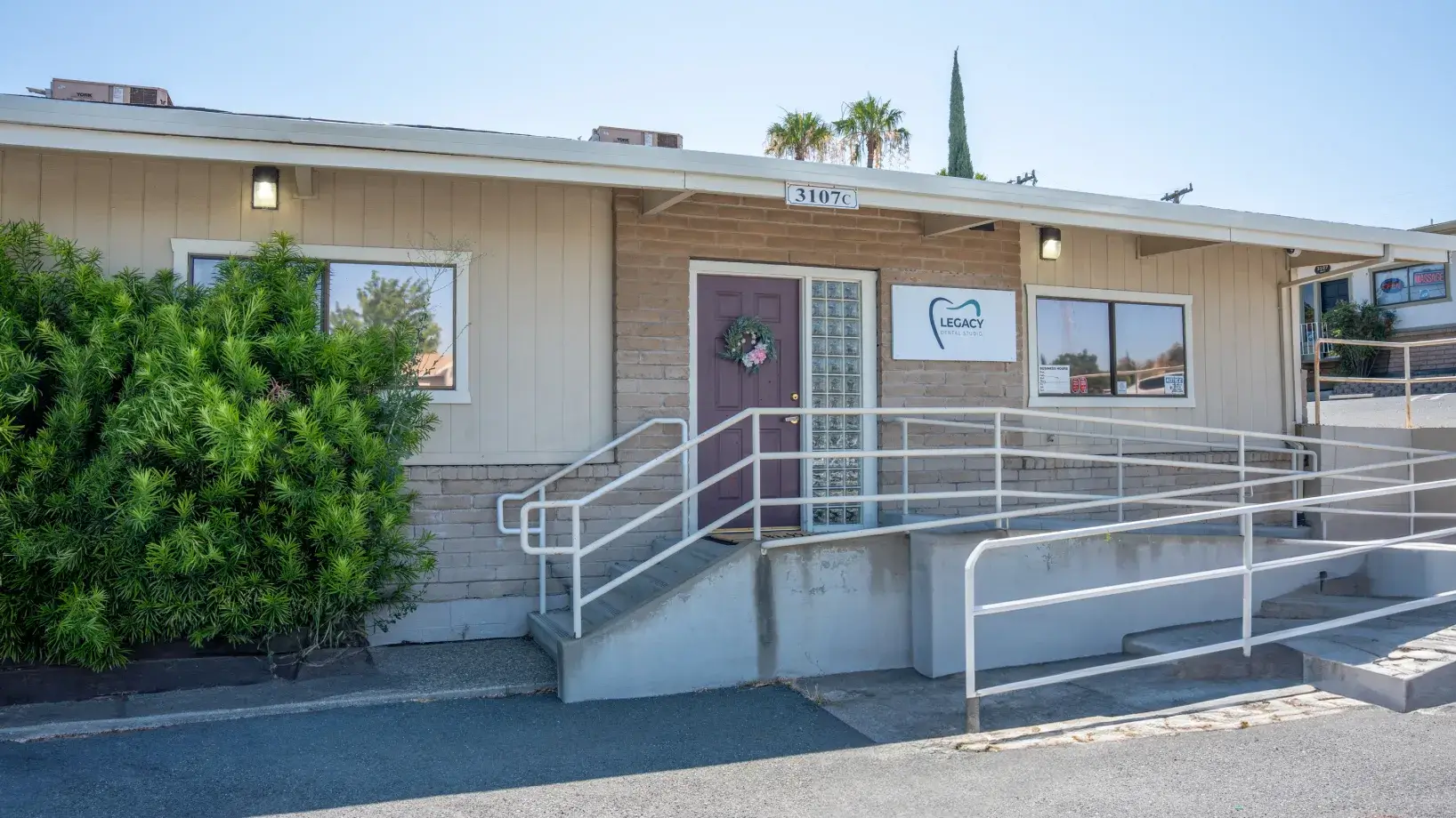 A beige building with a wheelchair ramp, displaying the "Legacy" sign above the door.
