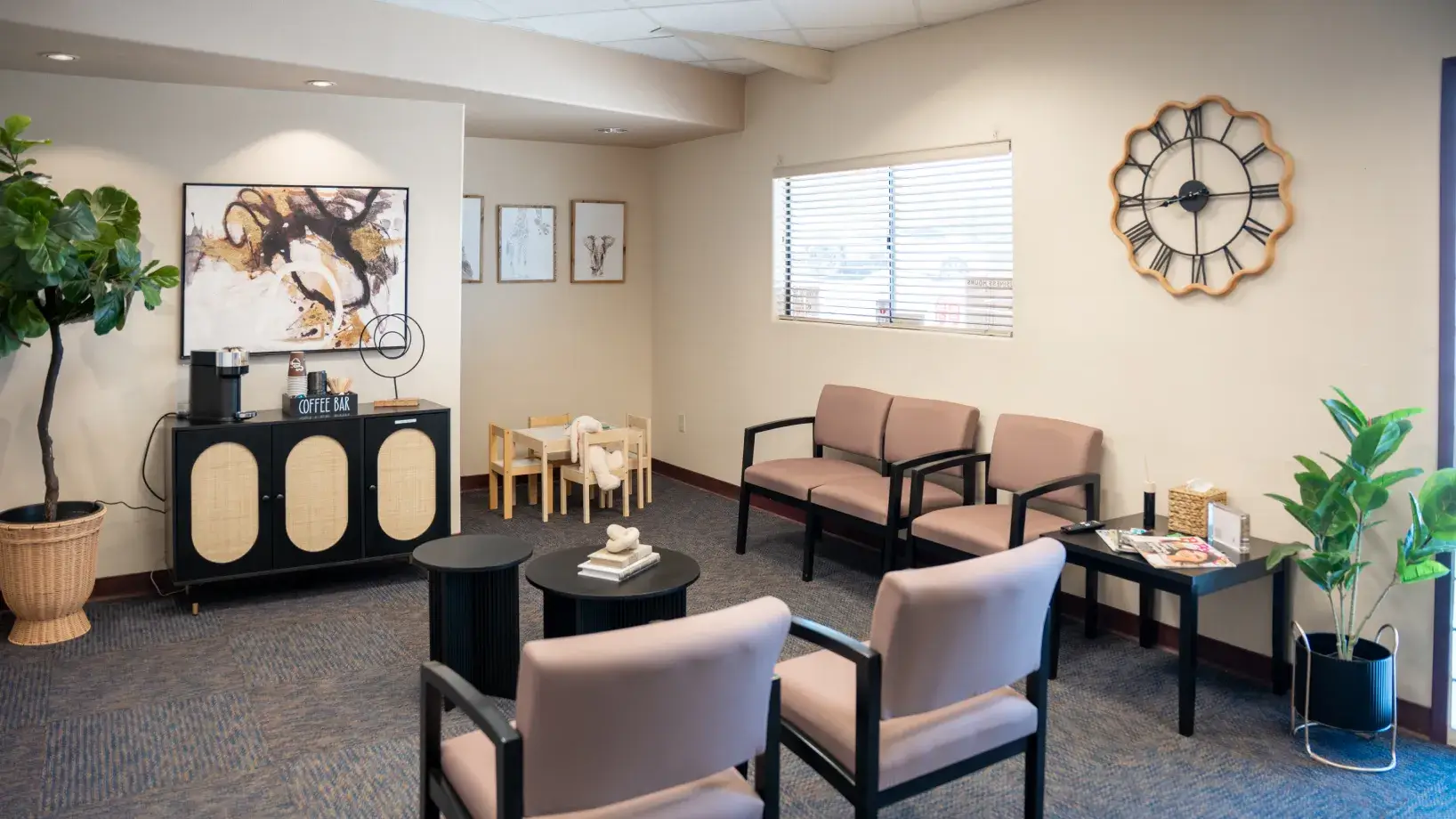A waiting room with chairs, a coffee station, a wall clock, and children's play area.