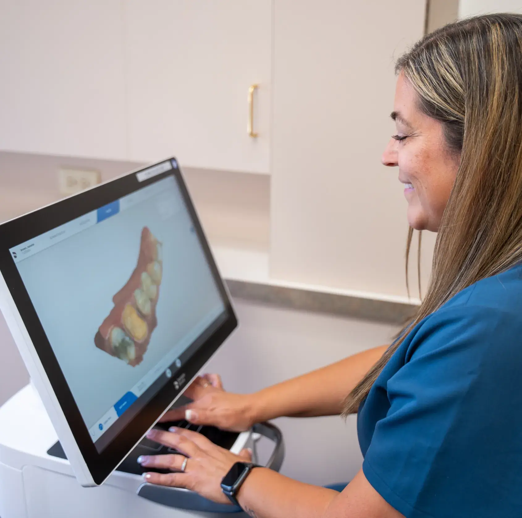 A dental professional examines a digital model of teeth on a computer screen.