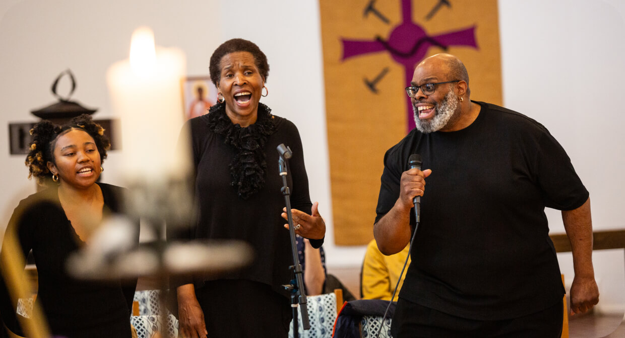 Three people singing into microphones during a church worship service
