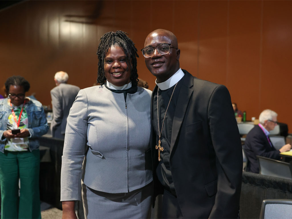 Presiding Bishop Yeheil Curry and Secretary Lucille Mills stand together in a room of people