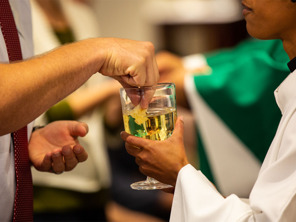 Hands holding communion bread and wine during a church service
