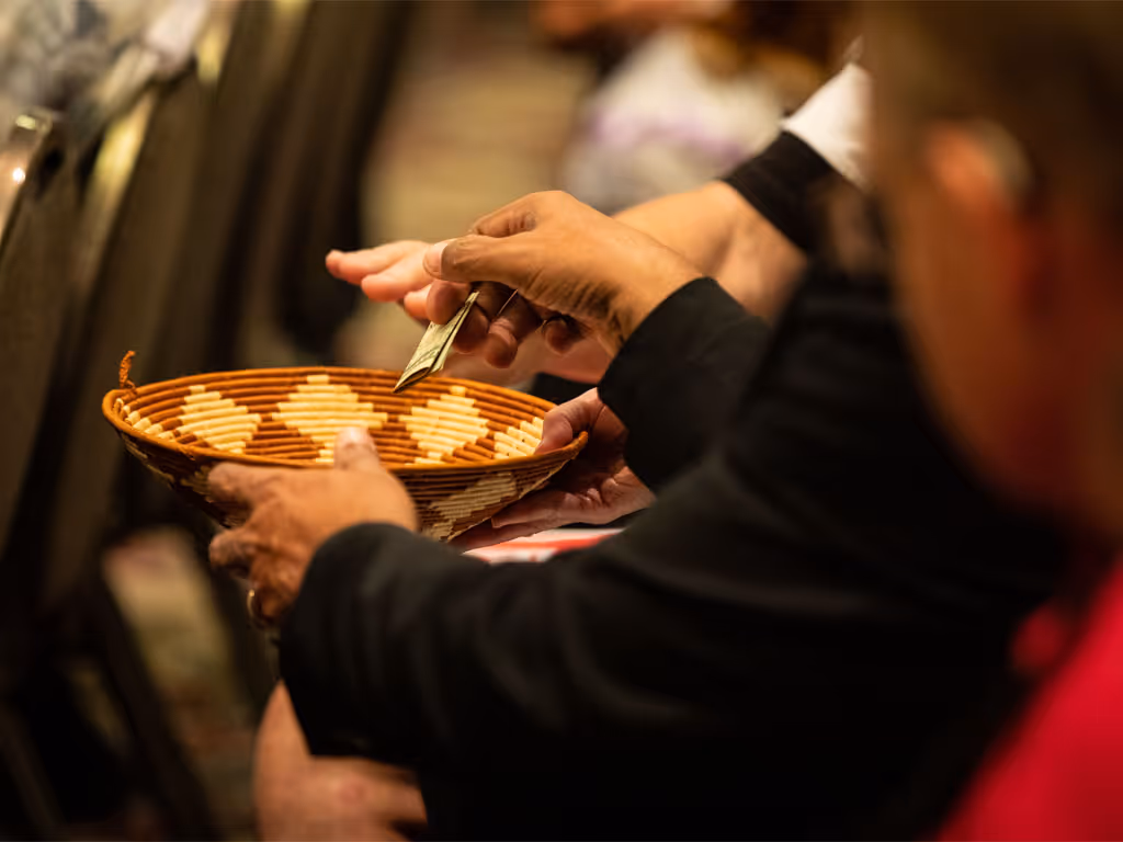 Hands holding a woven offering basket during a church service