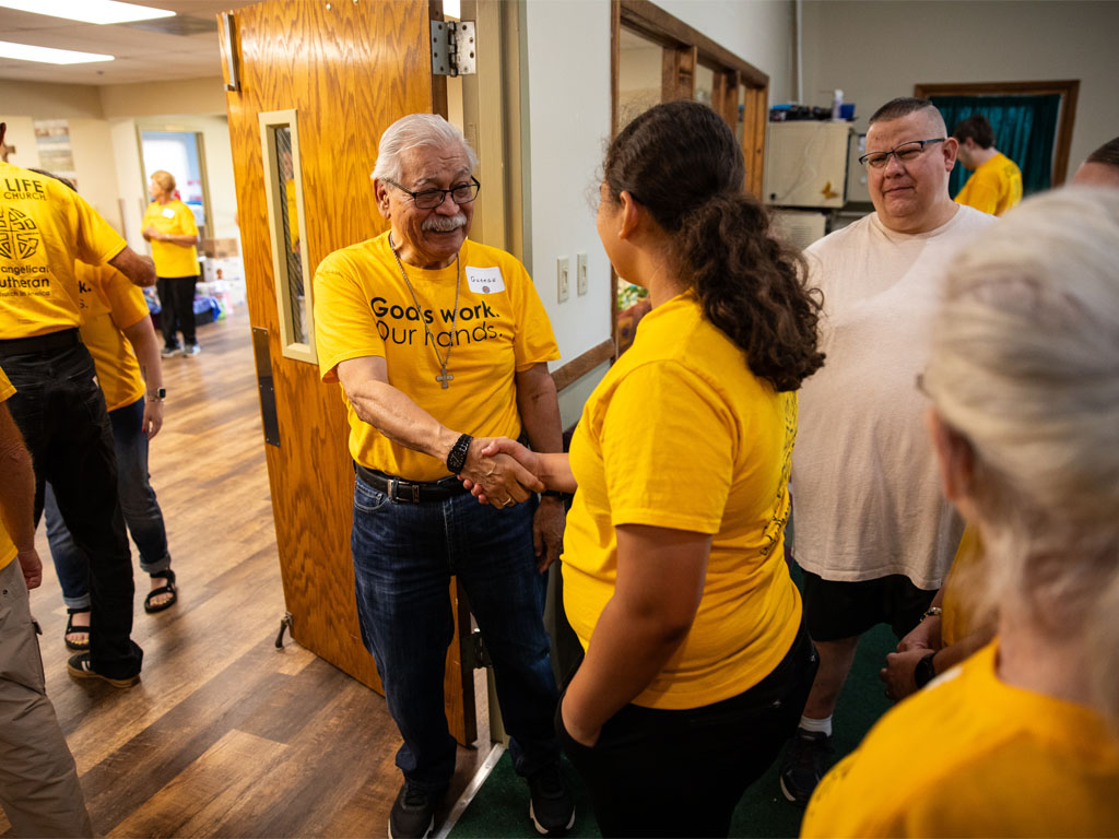 People wearing yellow shirts greeting one another indoors