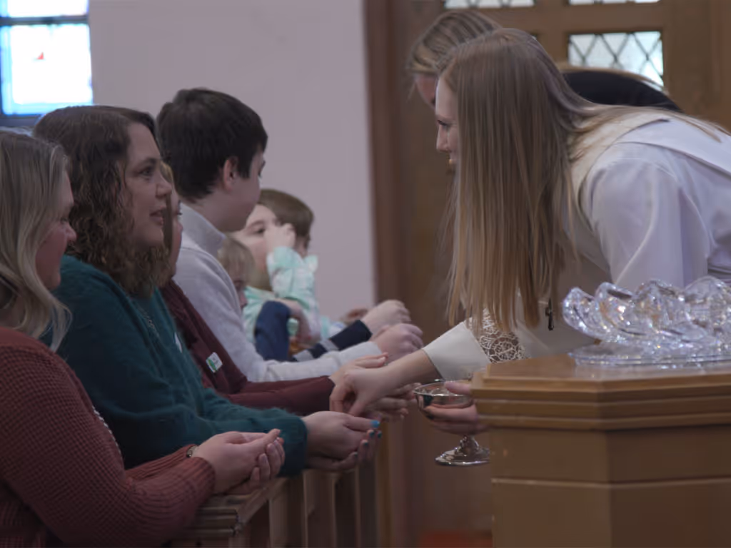 Clergy member distributing communion to congregants at an altar rail