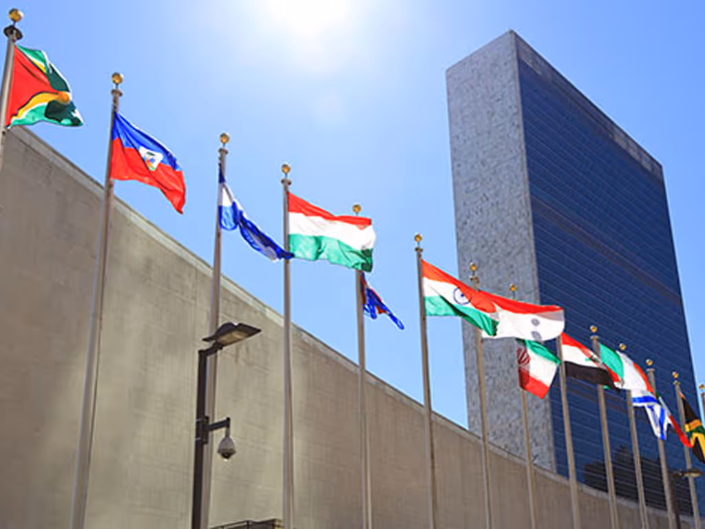 National flags flying on flagpoles outside a large modern building