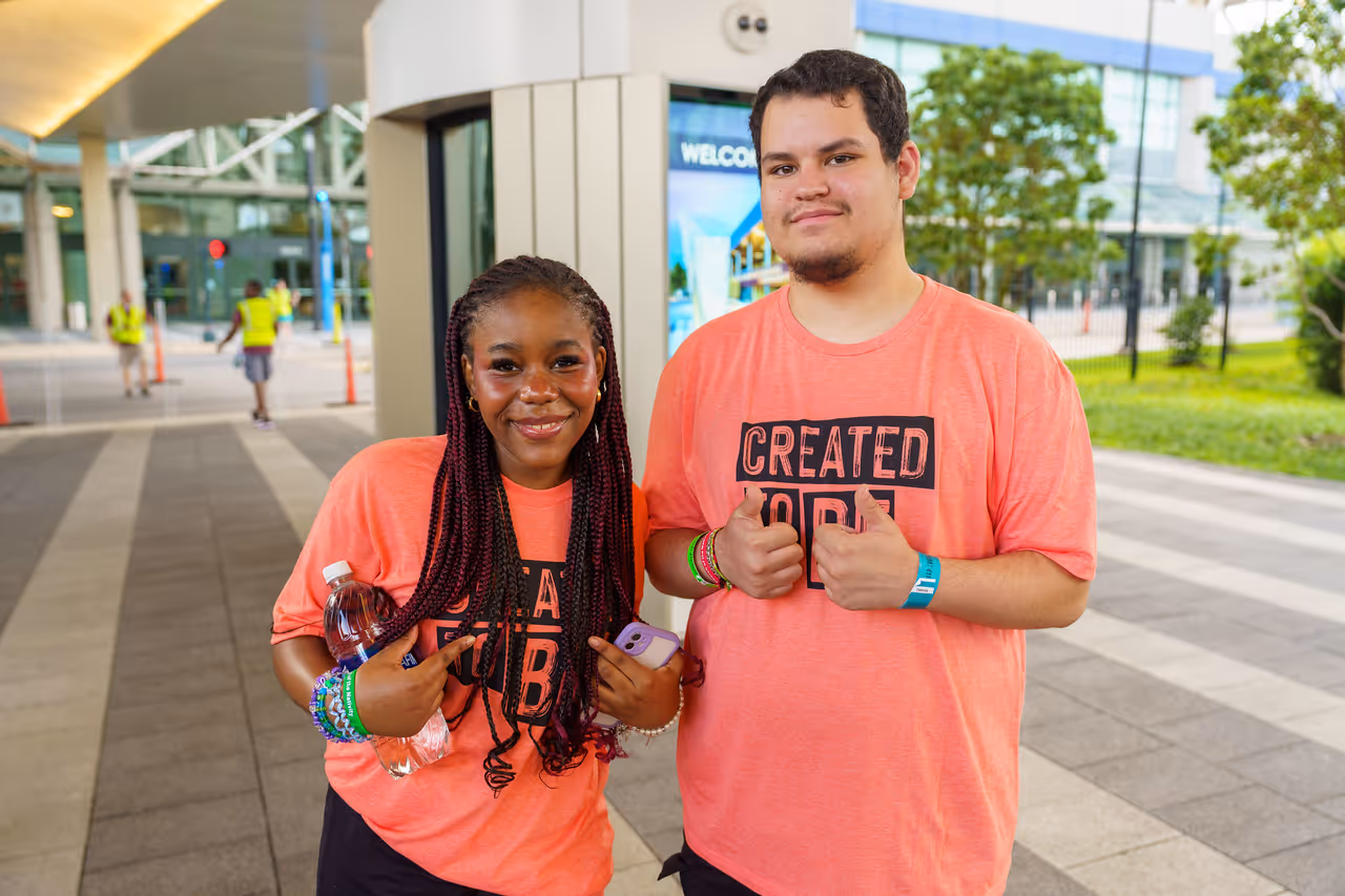 Two young people stand outside New Orleans Convention Center, both wearing orange shirts while attending the 2024 ELCA Youth Gathering.
