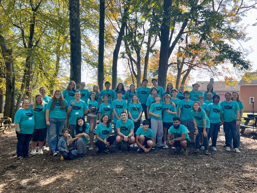 Group picture outside with people wearing a teal shirt 