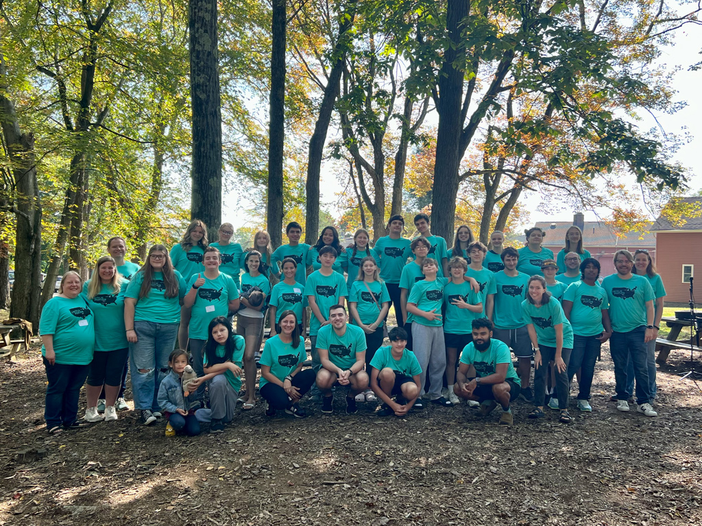 Group picture outside with people wearing a teal shirt 