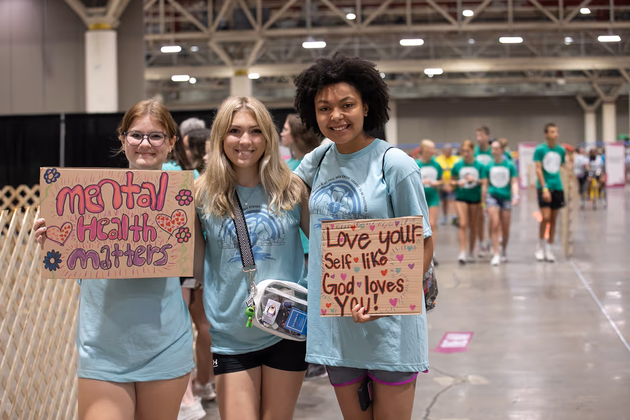 three girls holding signs in light blue shirts 