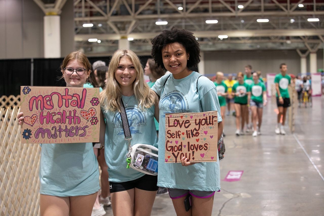 three girls holding signs in light blue shirts 