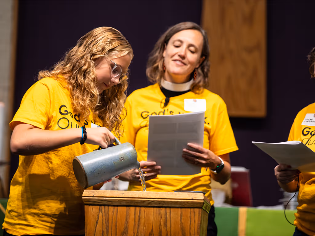 Two people standing at a lectern reading from a tablet