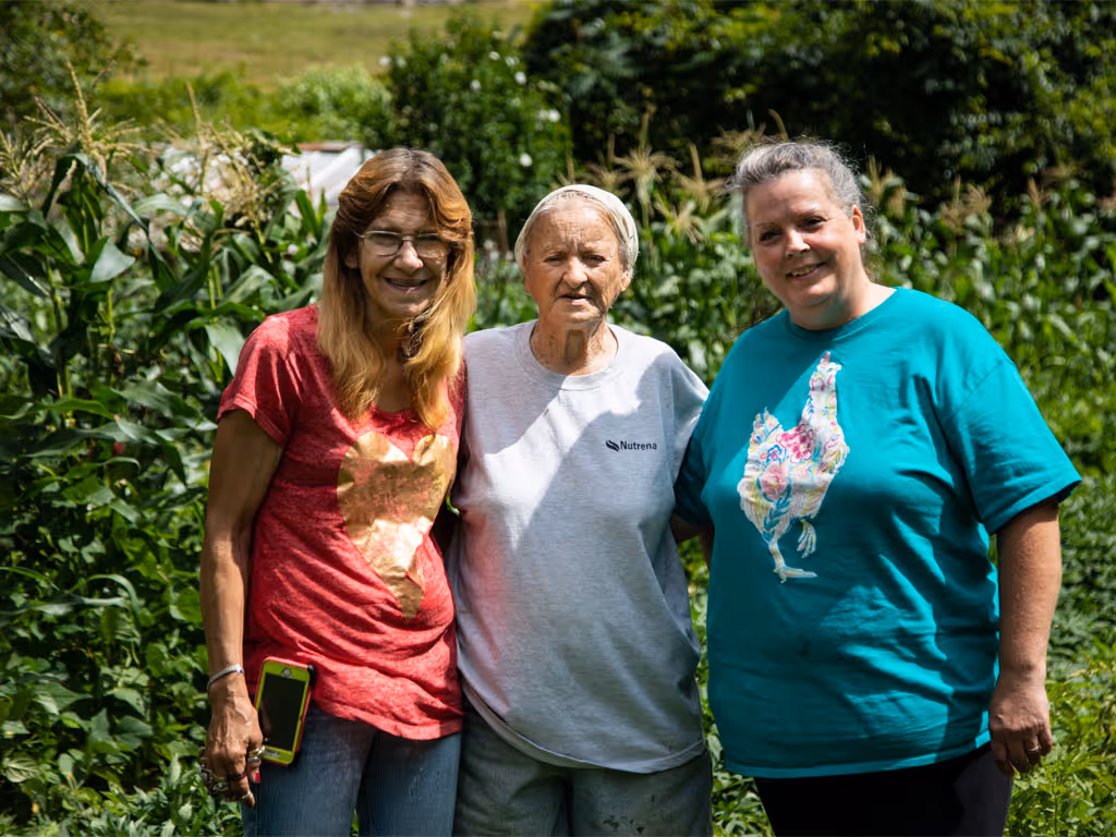 Three people standing together outdoors and smiling