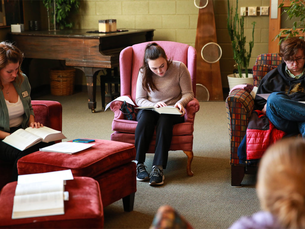 Young adults read in arm chairs, studying