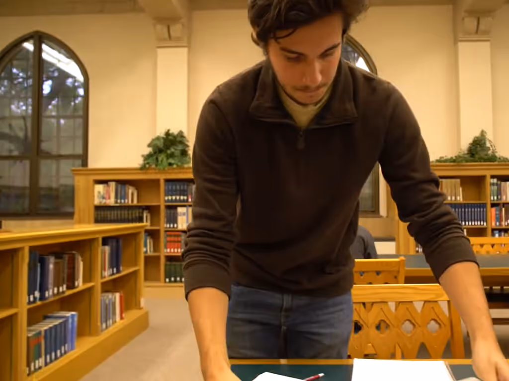 Person standing at a table in a library looking at materials