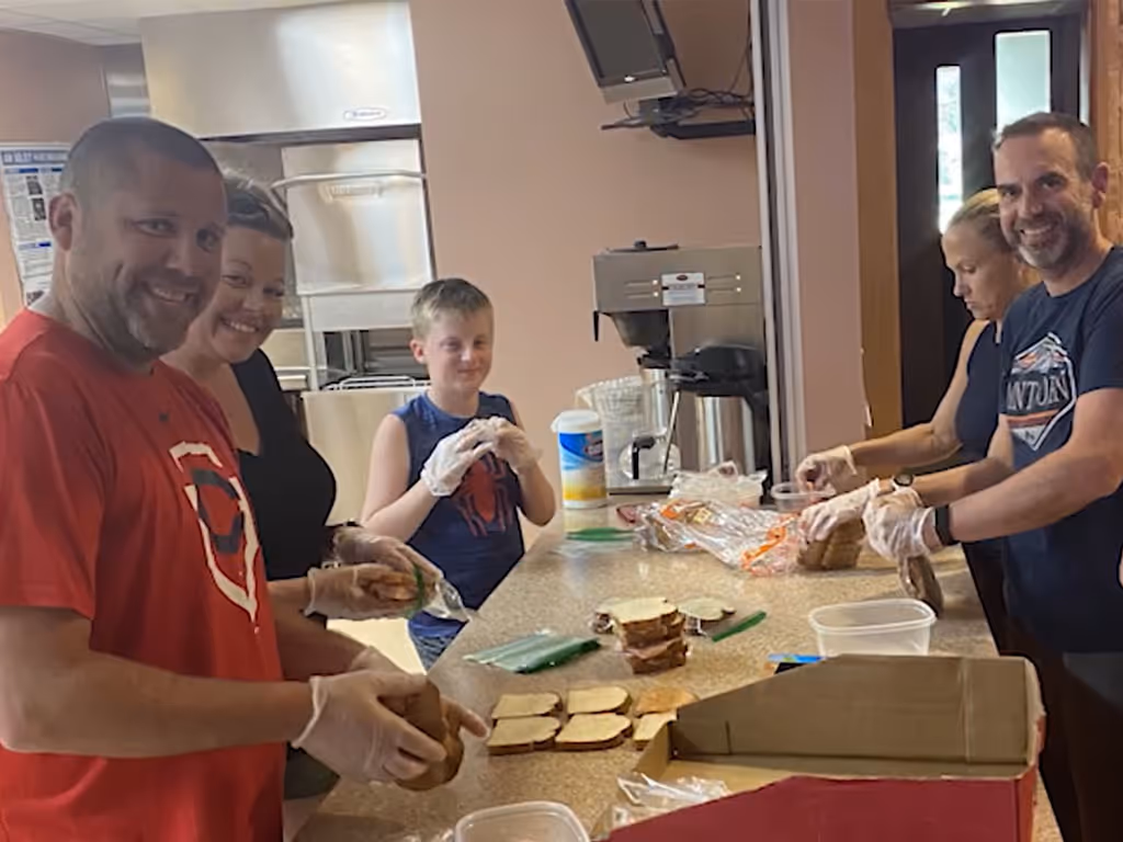 Adults and children preparing food together in a kitchen