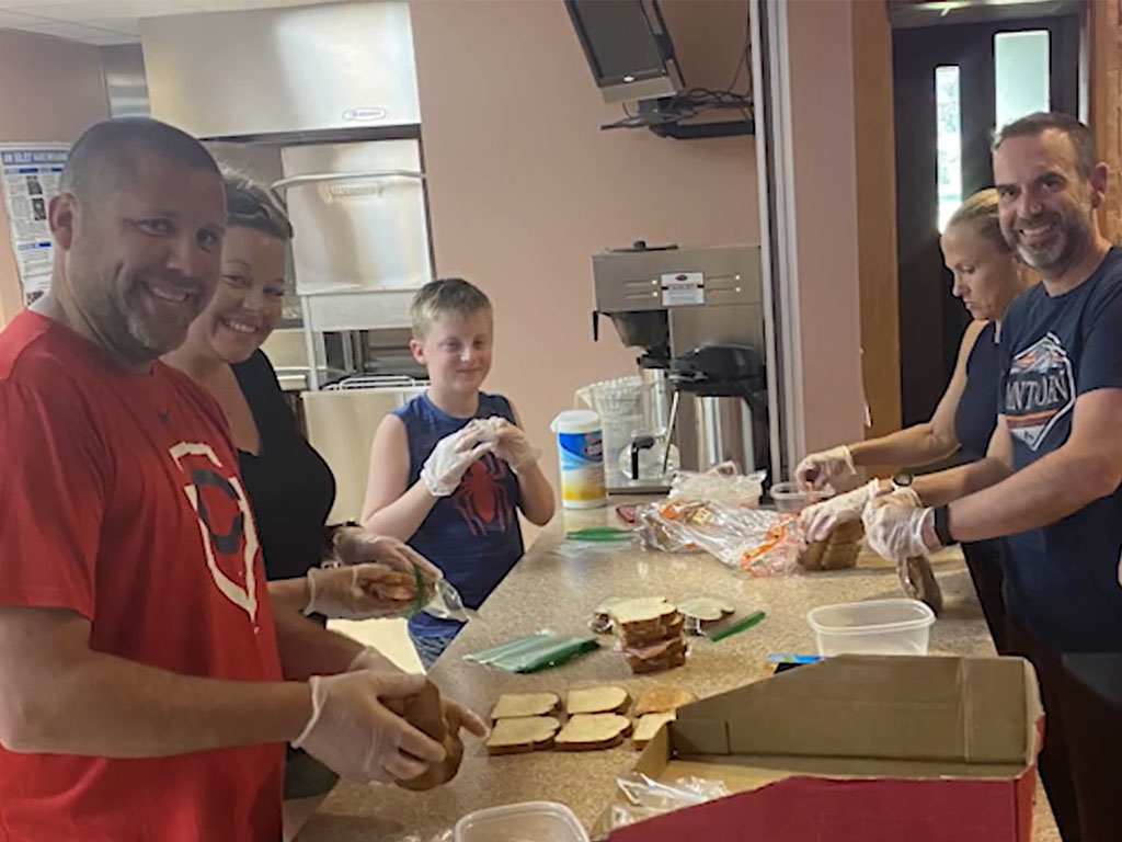 Adults and children preparing food together in a kitchen
