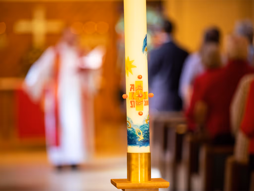 Lit church candle with people in the background
