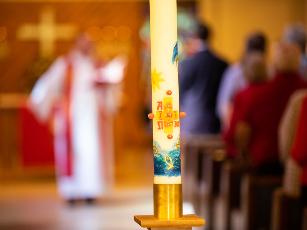 Lit church candle with people in the background