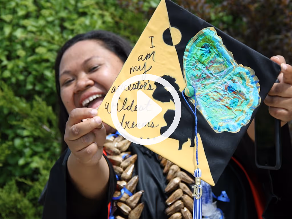 Person holding a handmade art piece with text and colorful decorations