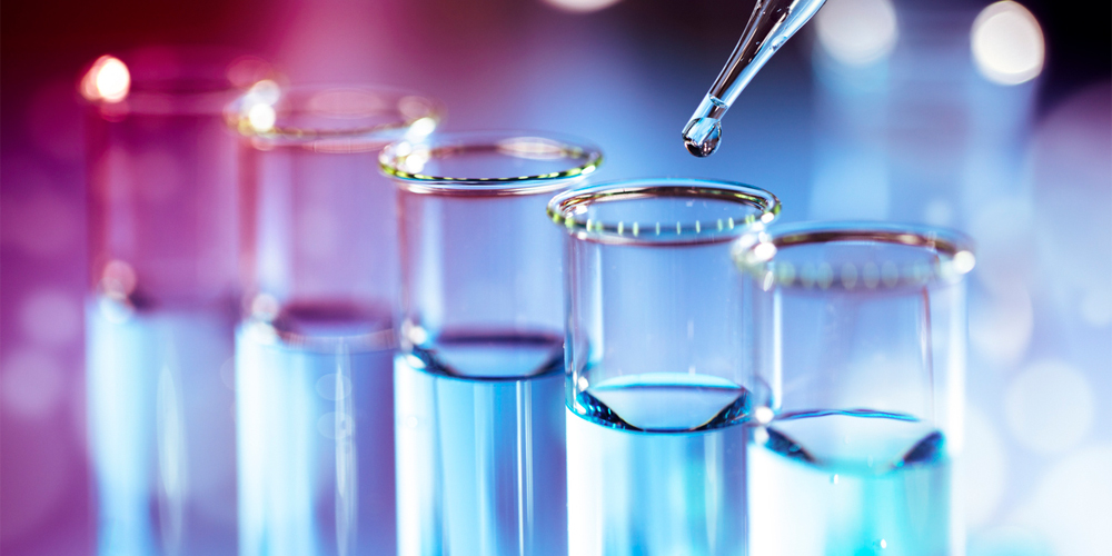 Two rows of lighted candles in glass jars sit on an altar with a blurred background.