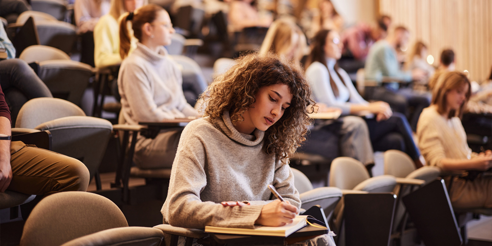 Clergy member holding a microphone while speaking with a group of children inside a church
