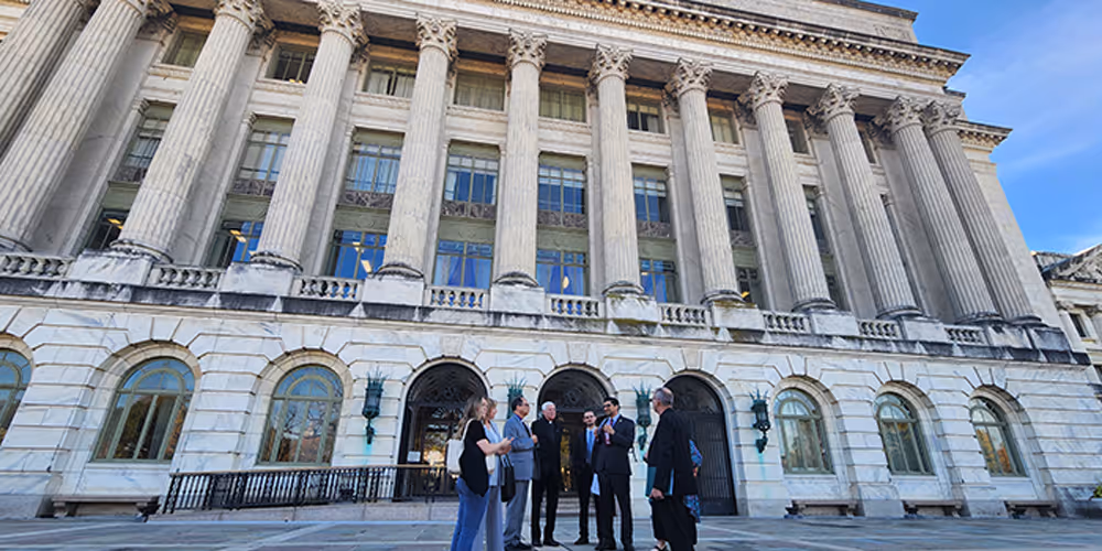 A woman writes in a notebook with a blue pen and blue ink as the camera looks over her left shoulder. 