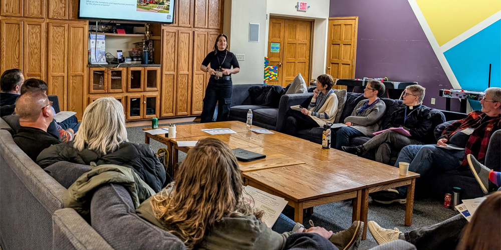 A group of people face a speaker in a casual setting