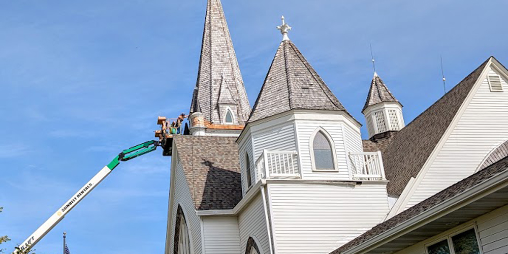 A man on a lift works on a church steeple