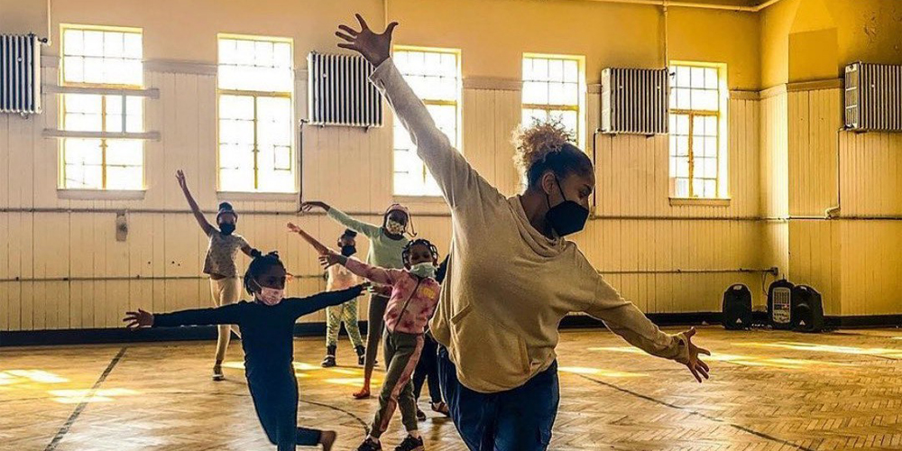 a teacher dances in front of a line of students mimicking her pose