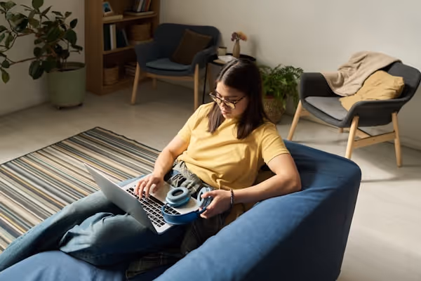 A woman works on a laptop in a cozy room.