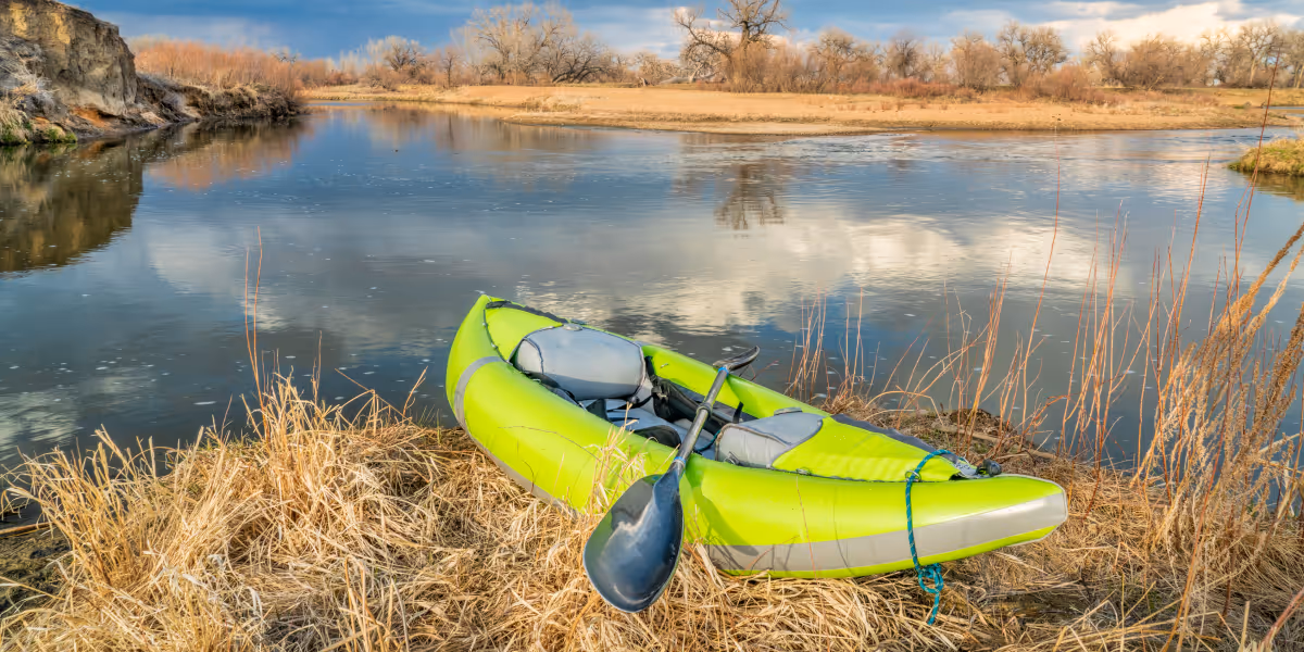 Green kayak sitting on the bank if a small lake in Platteville Colorado.