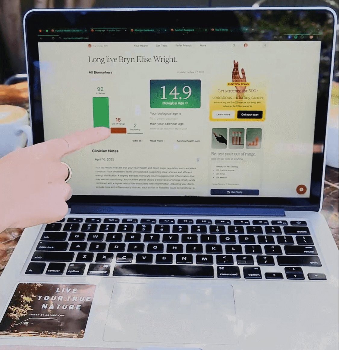 Person pointing to Function Health dashboard on a laptop screen showing biomarker results and biological age score