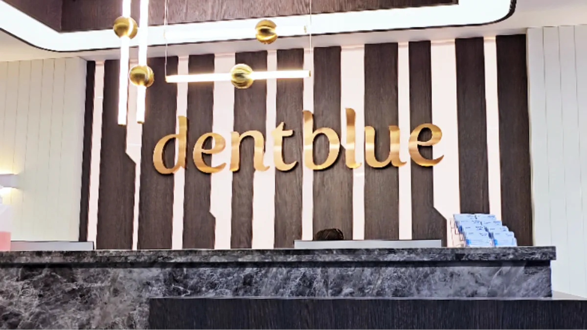 Gold dentblue sign on wood panel wall above marble front desk