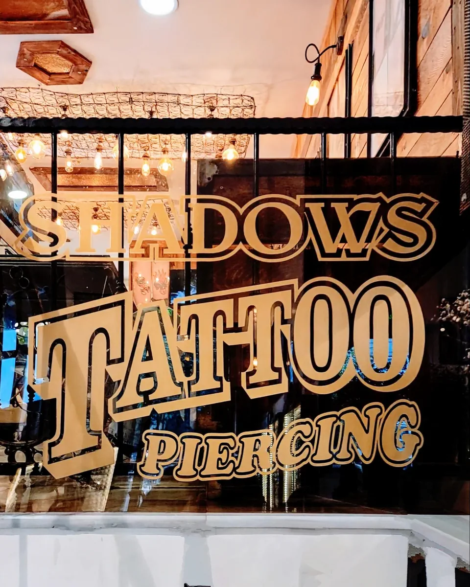 Gold-painted Shadows Tattoo & Piercing sign on studio window