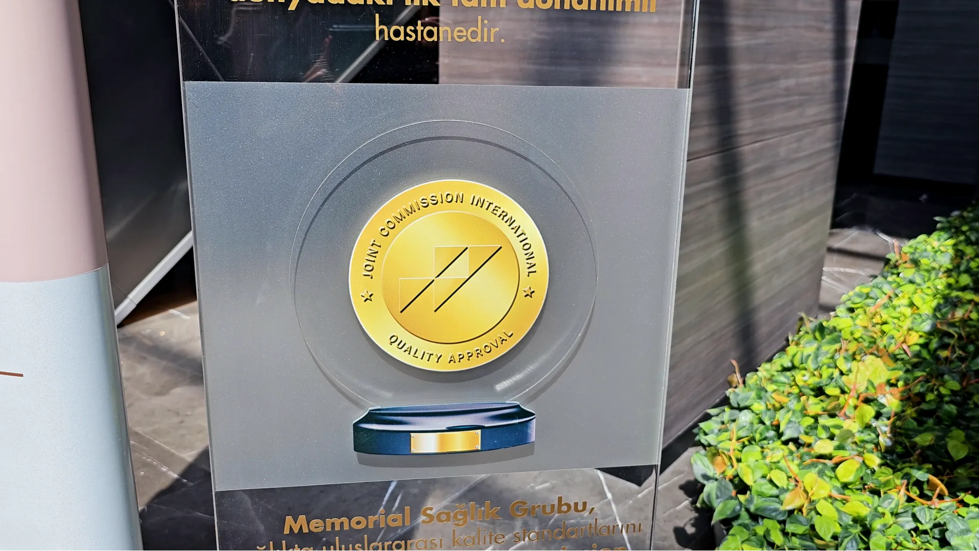 A gold Joint Commission International accreditation sign displayed at the entrance of Memorial Hospital in Istanbul.