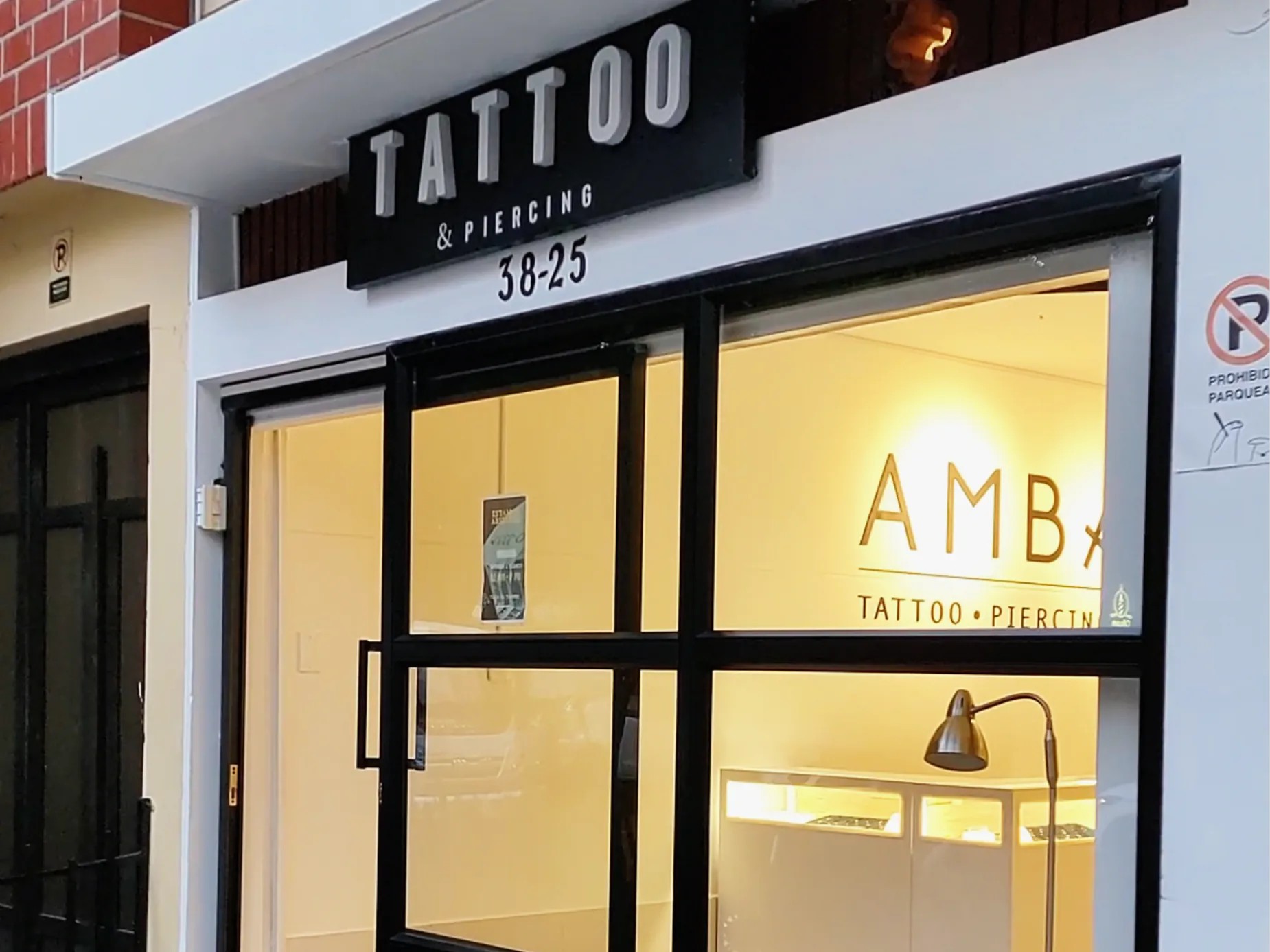 The entrance of AMBx Tattoo & Piercing studio in Medellín, Colombia, with a bright interior and signage promoting piercings.