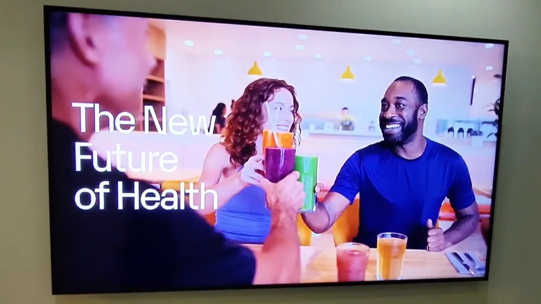 TV display inside Love.Life showing people cheering smoothies with the slogan "The New Future of Health."
