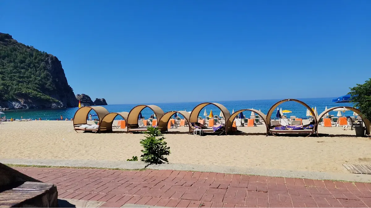 Daybeds and tents set up on Alanya beach in Turkey with clear blue sky and sea