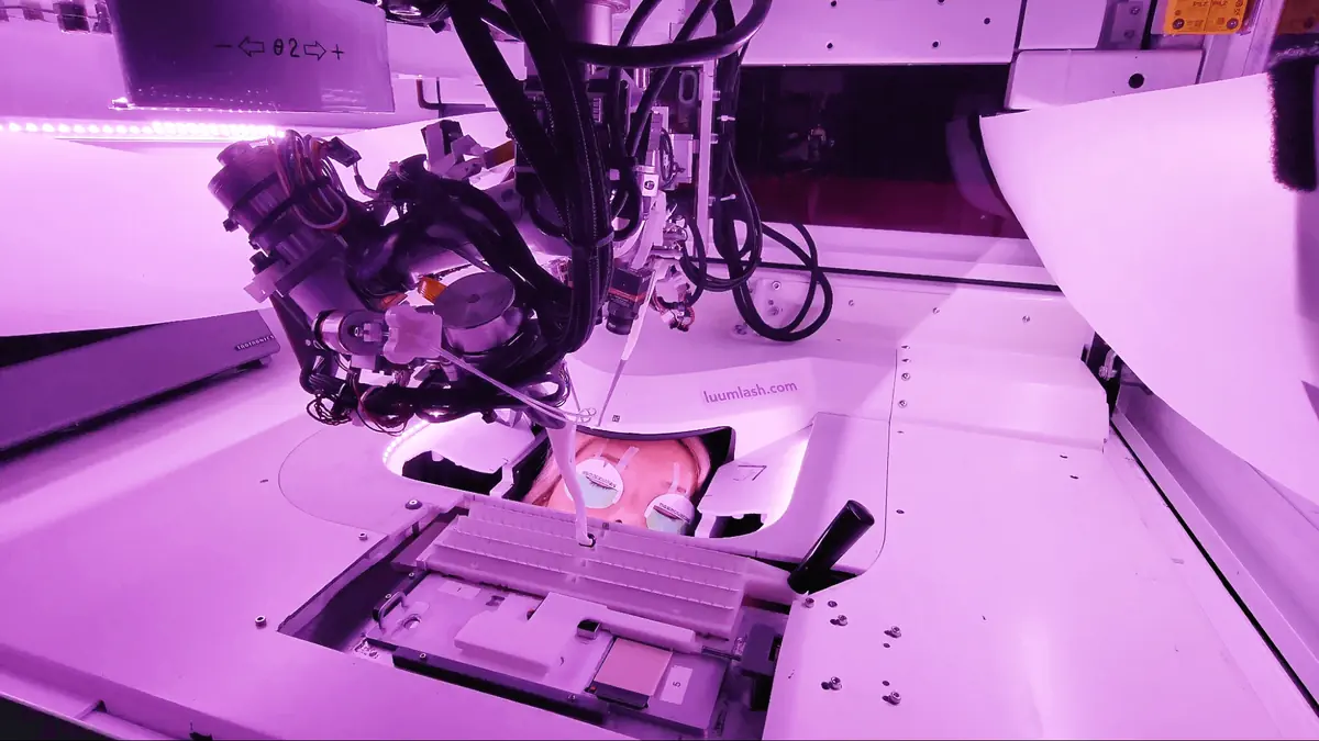 A close-up view of the LuumLash robotic system for futuristic eyelash extensions, glowing under purple lighting.  