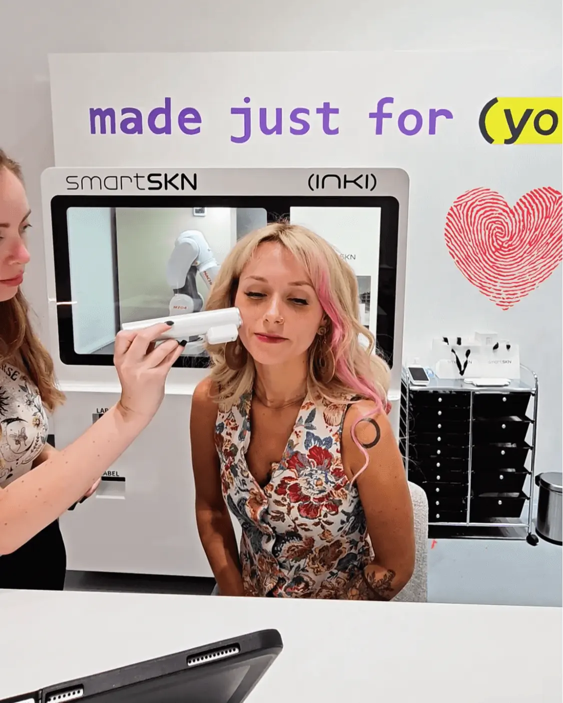 A woman receiving a SmartSKN facial skin scan at a futuristic beauty clinic in California, with the device analyzing her complexion.  