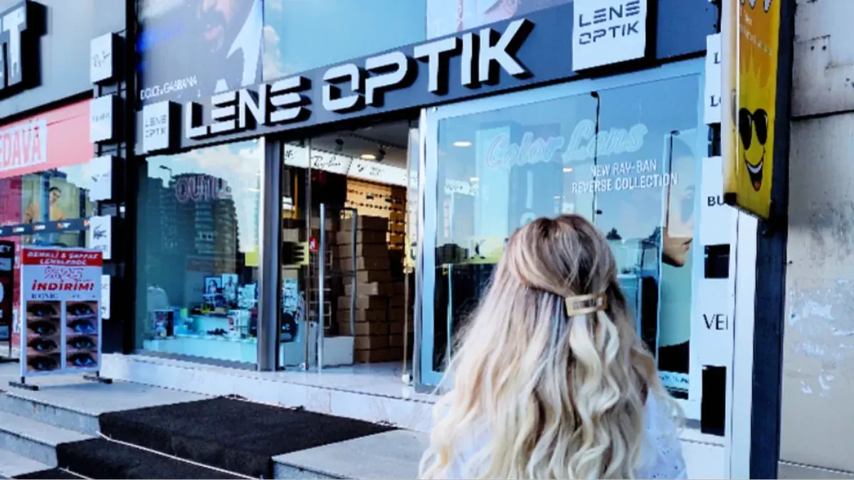 Woman with long blonde hair standing outside Lens Optik eyewear store in Istanbul.
