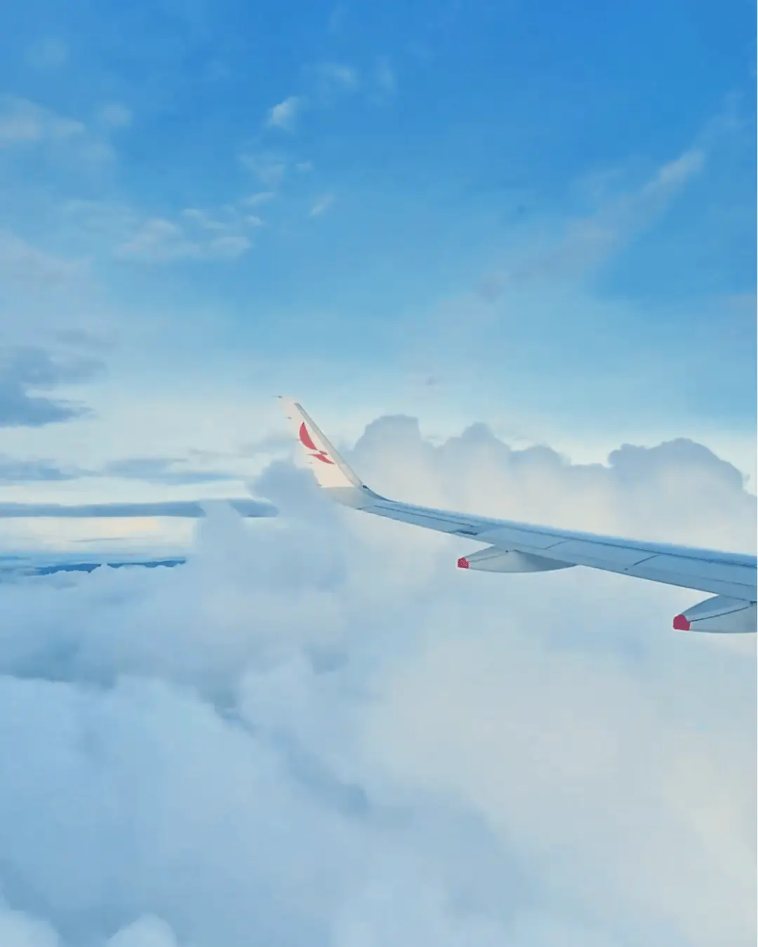 Airplane wing flying above the clouds on the way to Medellín, Colombia for dental tourism.