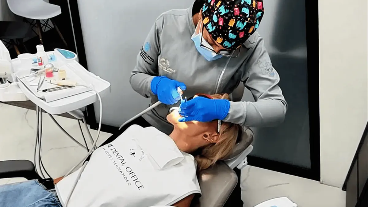 A dentist in Medellín performing a professional dental cleaning on a patient in a modern clinic.