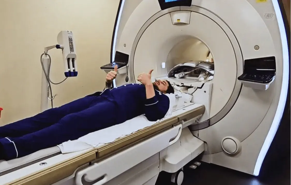 Patient giving a thumbs up while undergoing an affordable full-body MRI scan in the U.S., highlighting comfort and accessibility in preventive healthcare imaging.