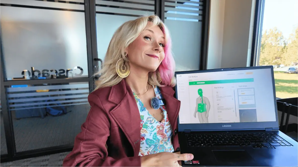 Woman smiling while holding a laptop displaying full body MRI scan results with highlighted key findings.