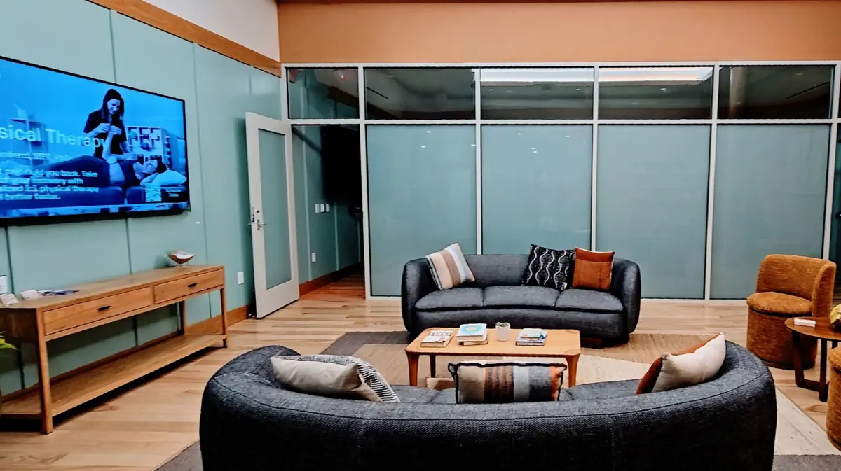 Cozy lounge area with modern sofas, coffee table, and TV inside Love.Life Health Club