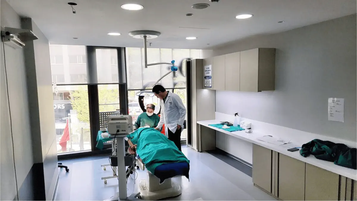 Modern surgery room in Istanbul with doctors performing a hair transplant procedure on a patient covered in a green drape.