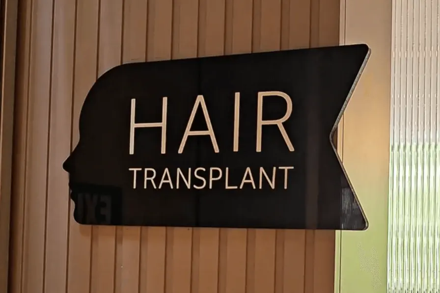 Hair transplant sign inside a modern Istanbul clinic with sleek wooden wall background.